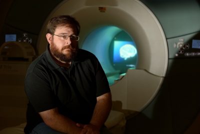 Stephen LaConte sits in front of an MRI scanner