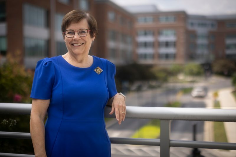 C. Kathleen Dorey standing by a railing at the Virginia Tech Carilion School of Medicine building.