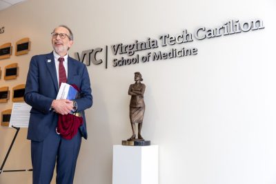 Dean Lee Learman stands beside a statue of Henriett Lacks at the Virginia Tech Carilion School of Medicine.