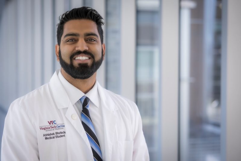 Man wearing VTCSOM white coat standing in hallway