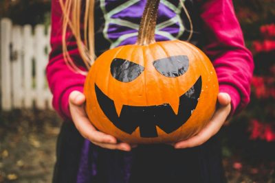 Child in costume holding jack'o lantern.