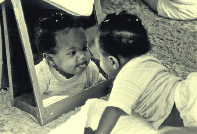 Baby plays in mirror.
