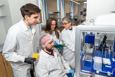 Virginia Tech researchers John Janiga, Dzenis Mahmutovic (seated), Katherine Brown, and lead investigator Carla Finkielstein work together in the Molecular Diagnostics Laboratory 