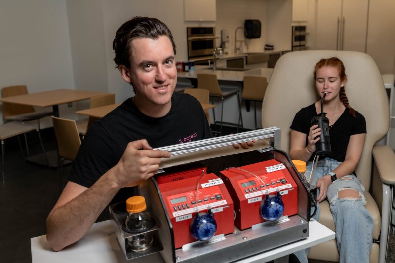 Graduate student holding a pump system and drinking through a tube