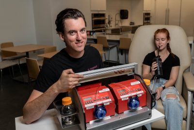 Graduate student holding a pump system and drinking through a tube