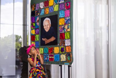 A young girl looks up toward the center of a quilt made in honor of Nikki Giovanni