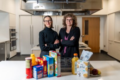 Brenda Davy and Alex DiFeliceantonio stand behind food items in a metabolic kitchen