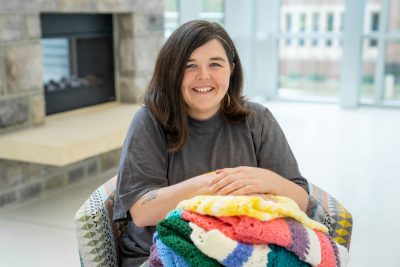Photo of Brittany Howell with baby blankets, with a fireplace in the background